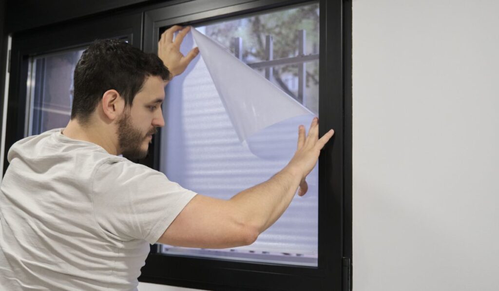 Man installing frosted window vinyl on window glass