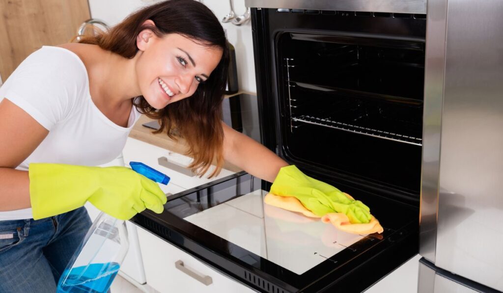 Woman Cleaning The Oven In Kitchen