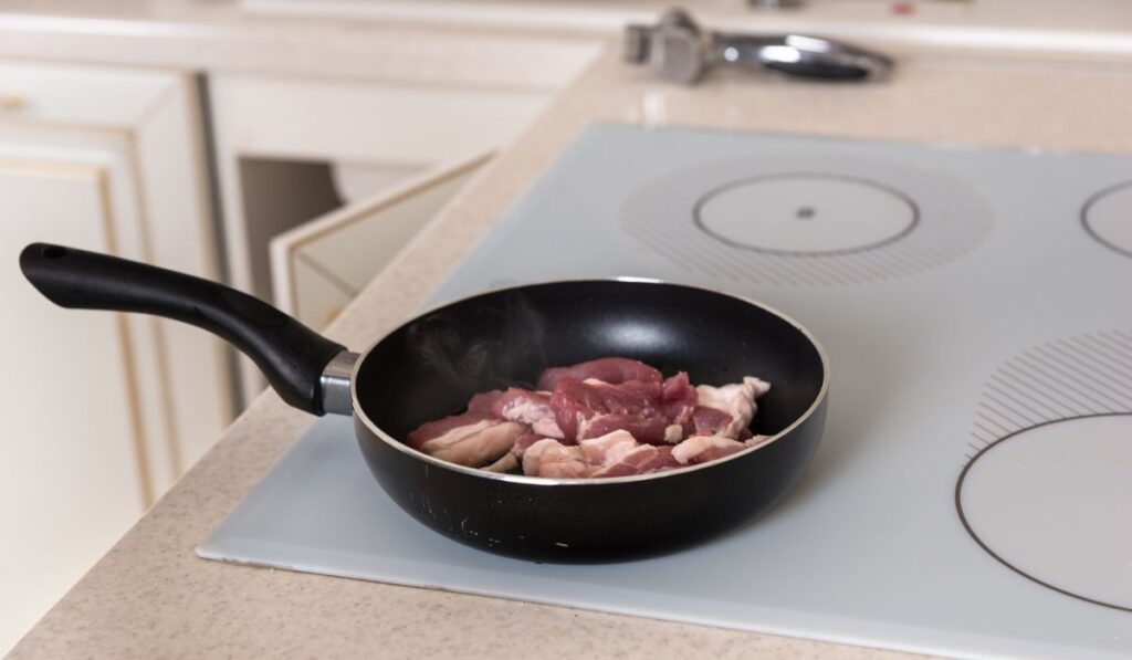 Raw Meat Cooking in Frying Pan on Stove Top