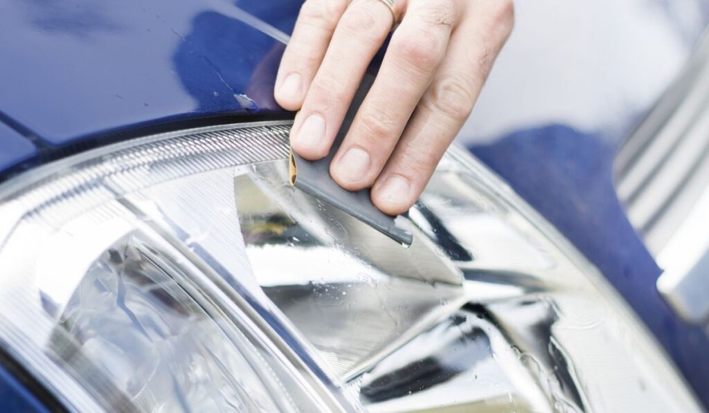 The car mechanic`s hand polishes with sandpaper and water frosted reflector glass