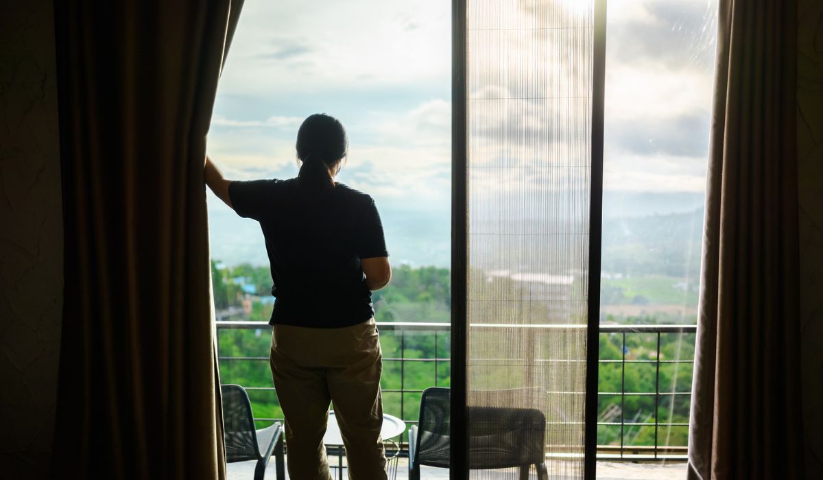 A woman open the curtain of the hotel room