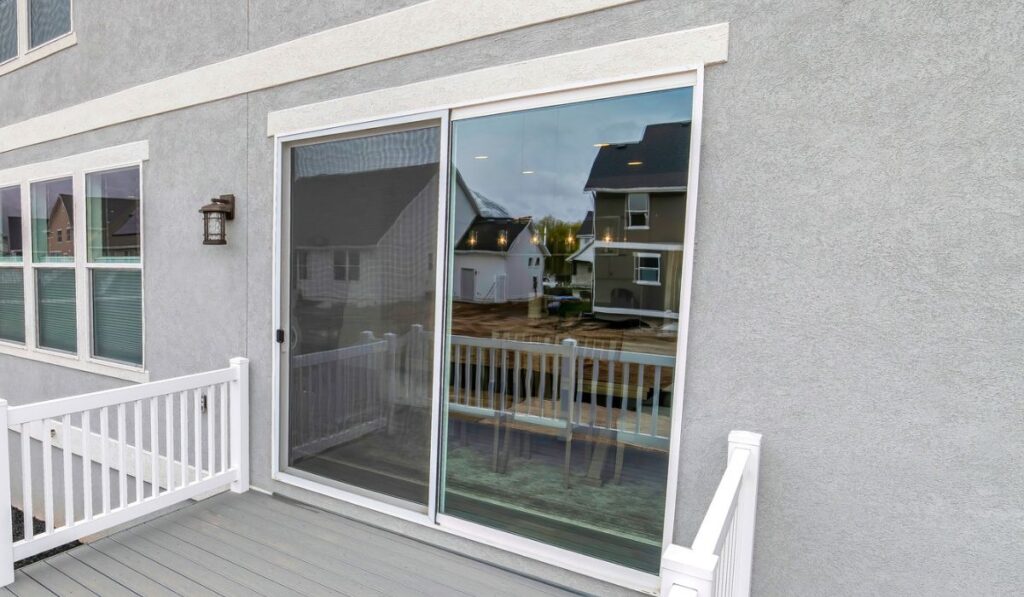 Deck of two storey house with sliding glass door and stairs leading to yard