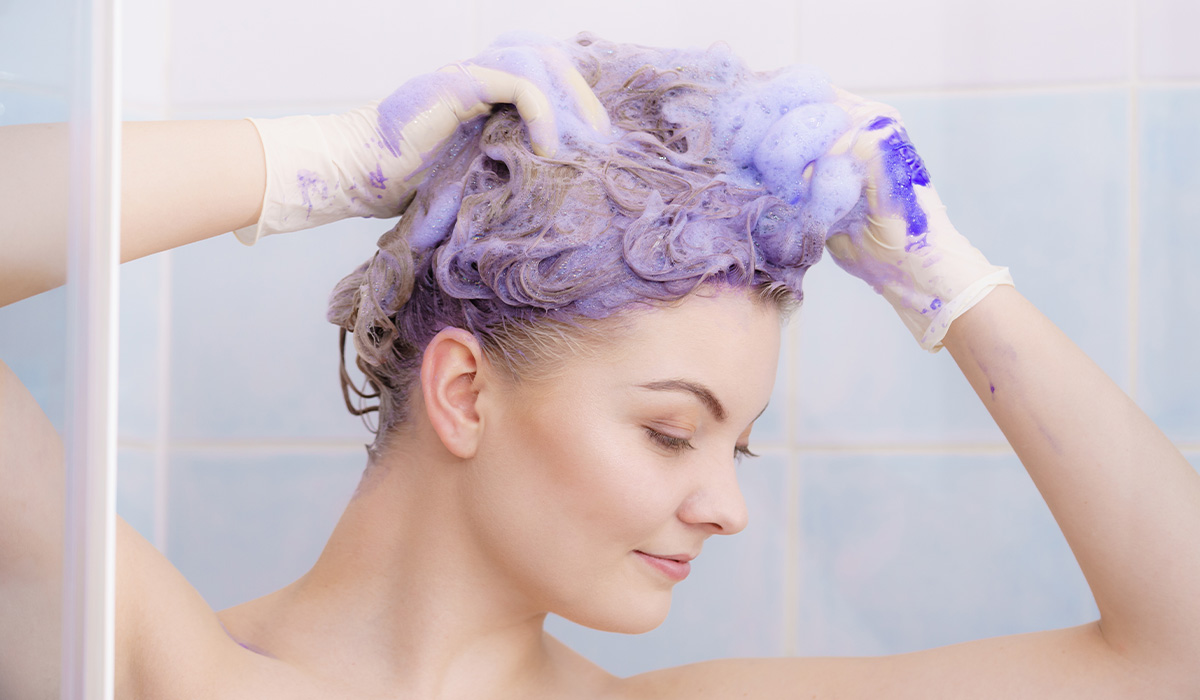 Woman in shower applying purple color toner
