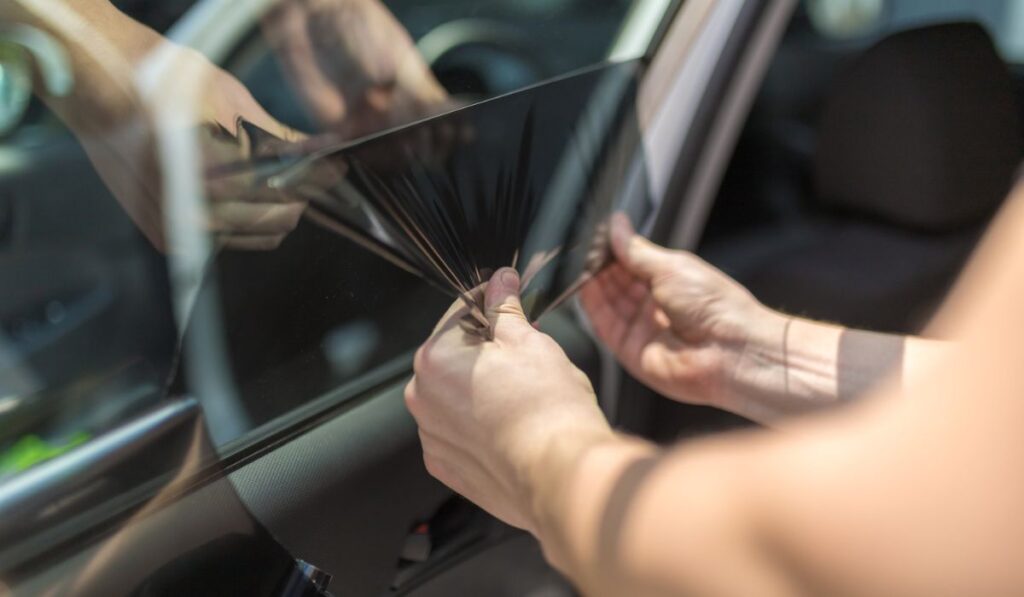 Close up of worker pulling off sun protection tinted foil from side car window