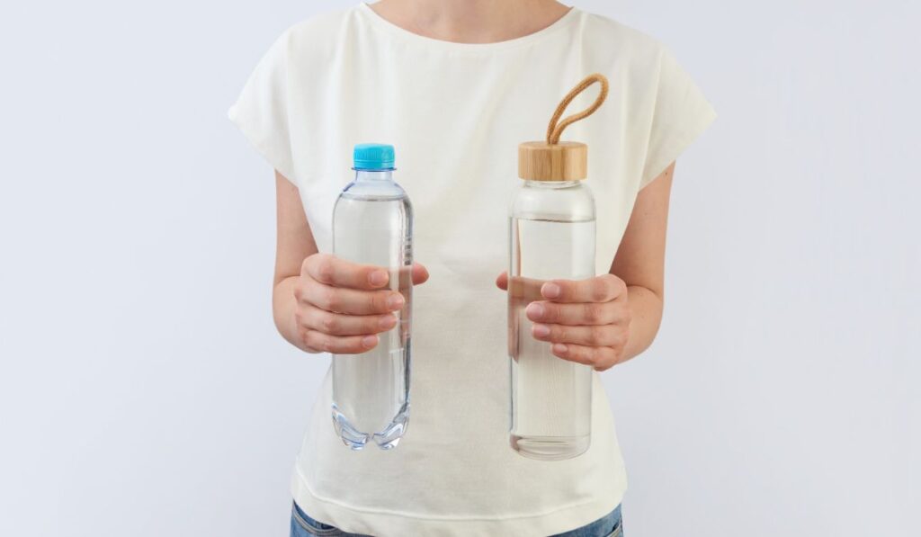 Glass and plastic bottles of clean fresh water in a woman`s hands