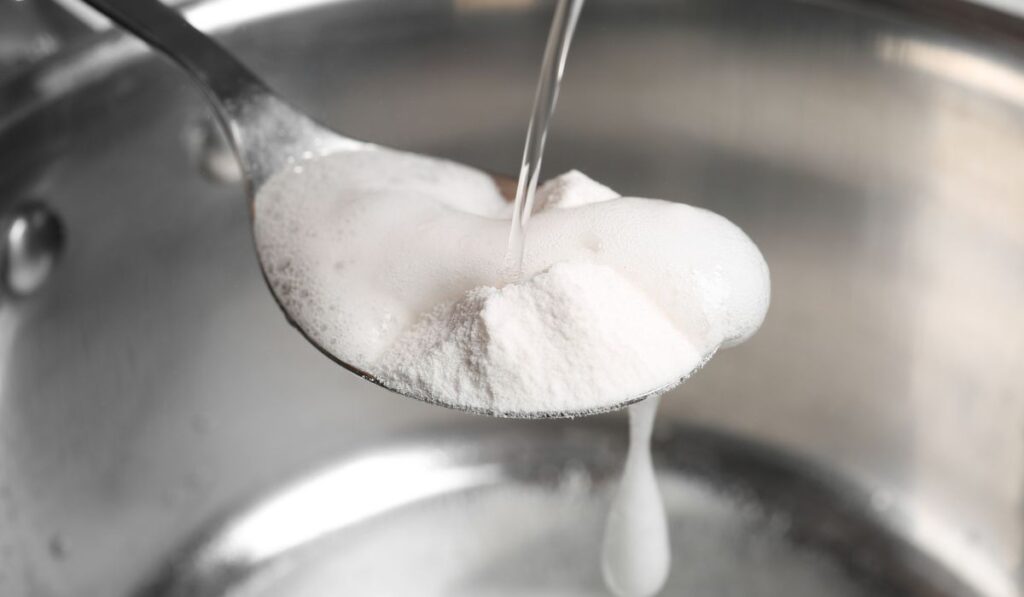 Pouring vinegar into spoon with baking soda