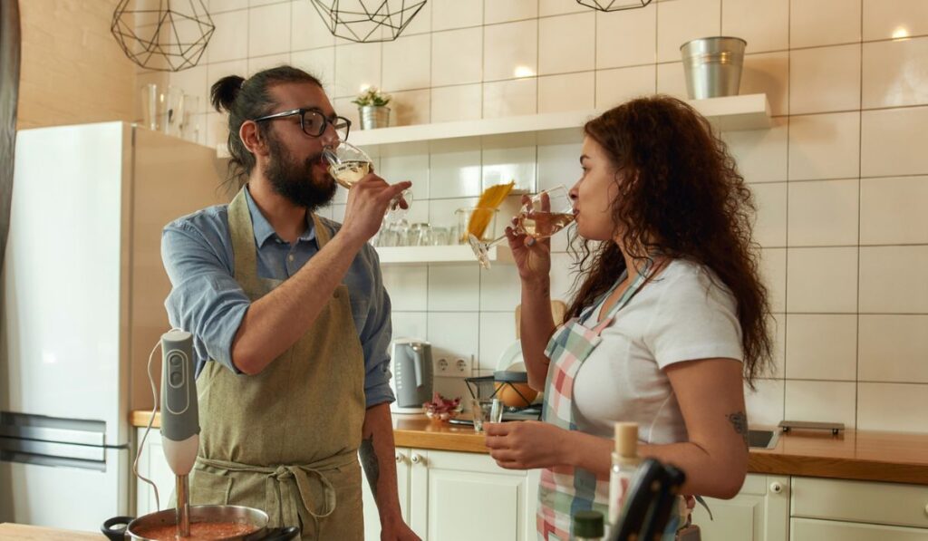 Italian man looking at his girlfriend while they are drinking white wine