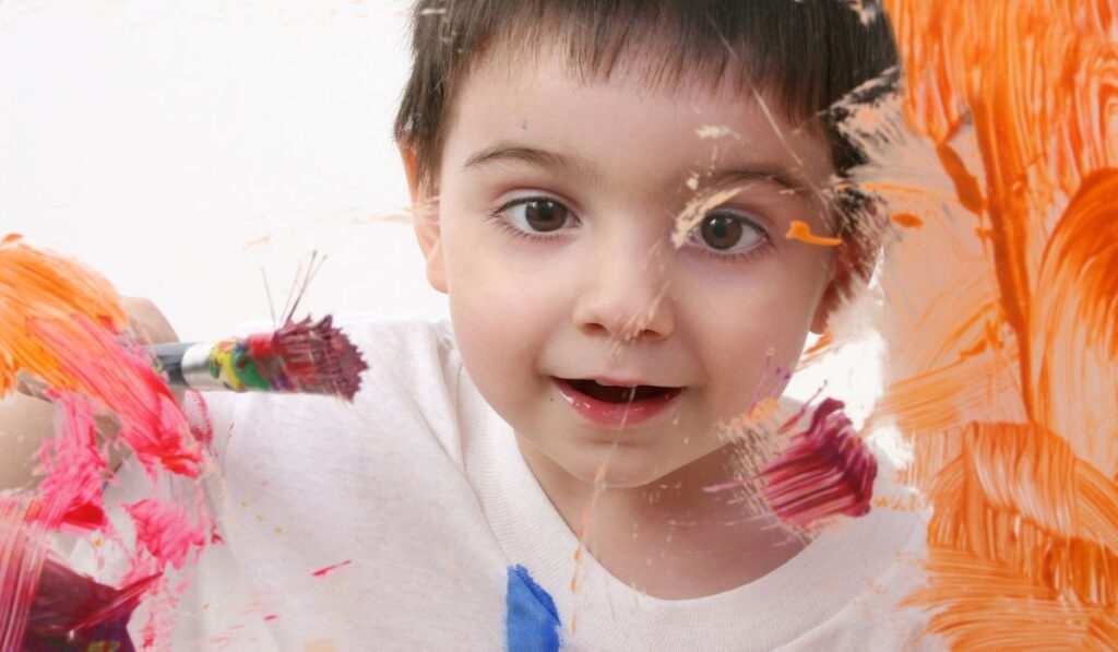 Adorable Toddler Boy Painting On Glass