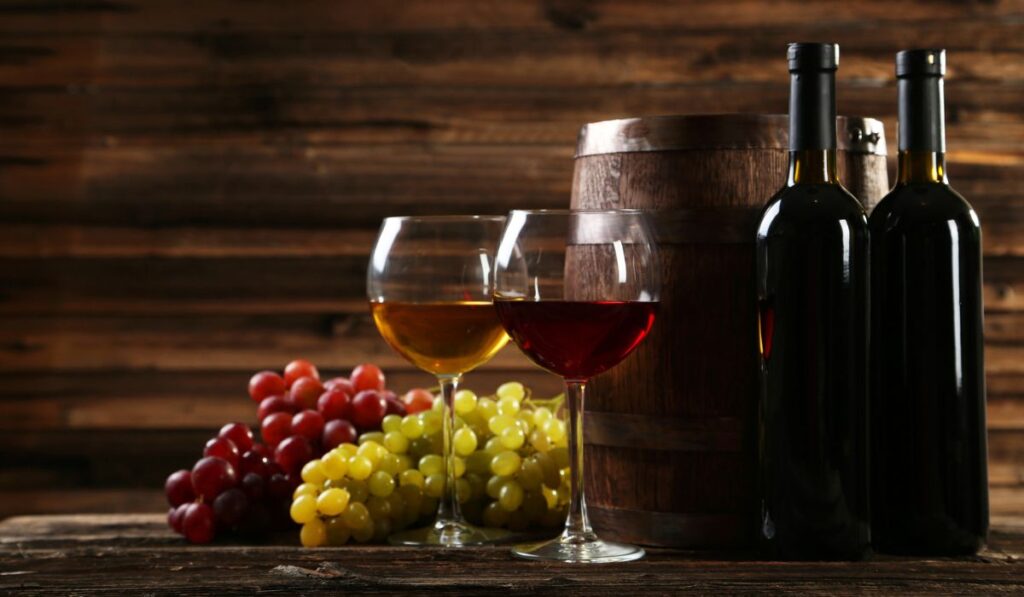 Glass of red and white wine with grapes on brown wooden background