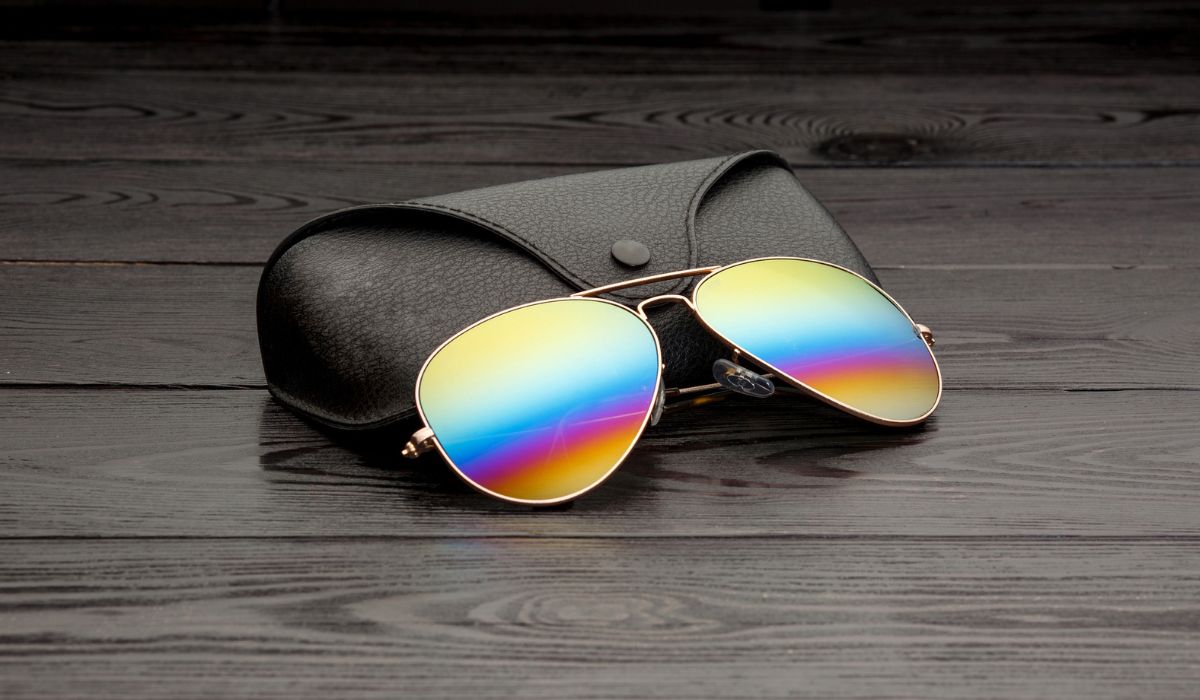 Summer aviator sunglasses with mirrored color lenses made of glass in a metal frame of gold color with a black leather case on